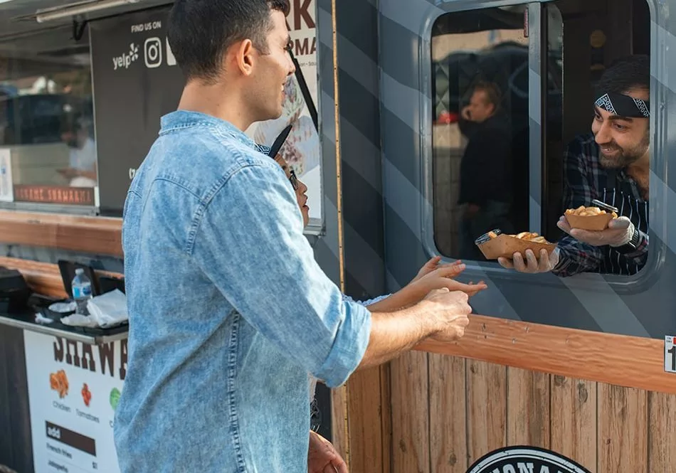 Two men standing in front of a food truck.