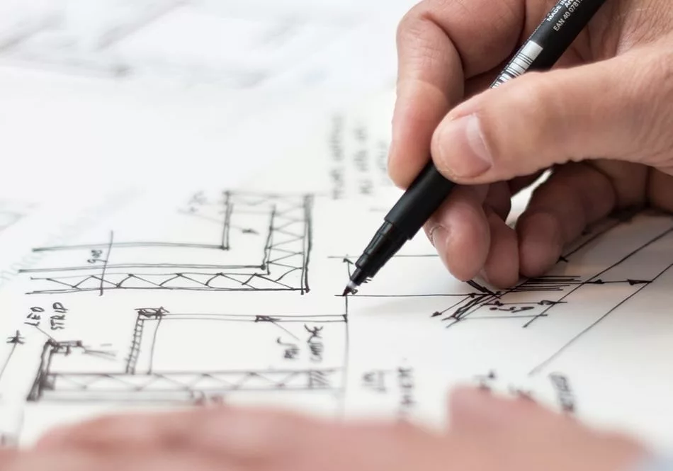 A man is drawing on a blueprint with a pen.