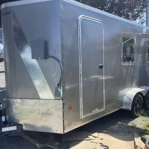 A silver, enclosed trailer is parked in a lot, ready to be bought and transformed into a food truck.