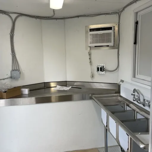 A compact kitchen, equipped with a sink and a refrigerator, is available for sale. It's an ideal choice for a food truck business.